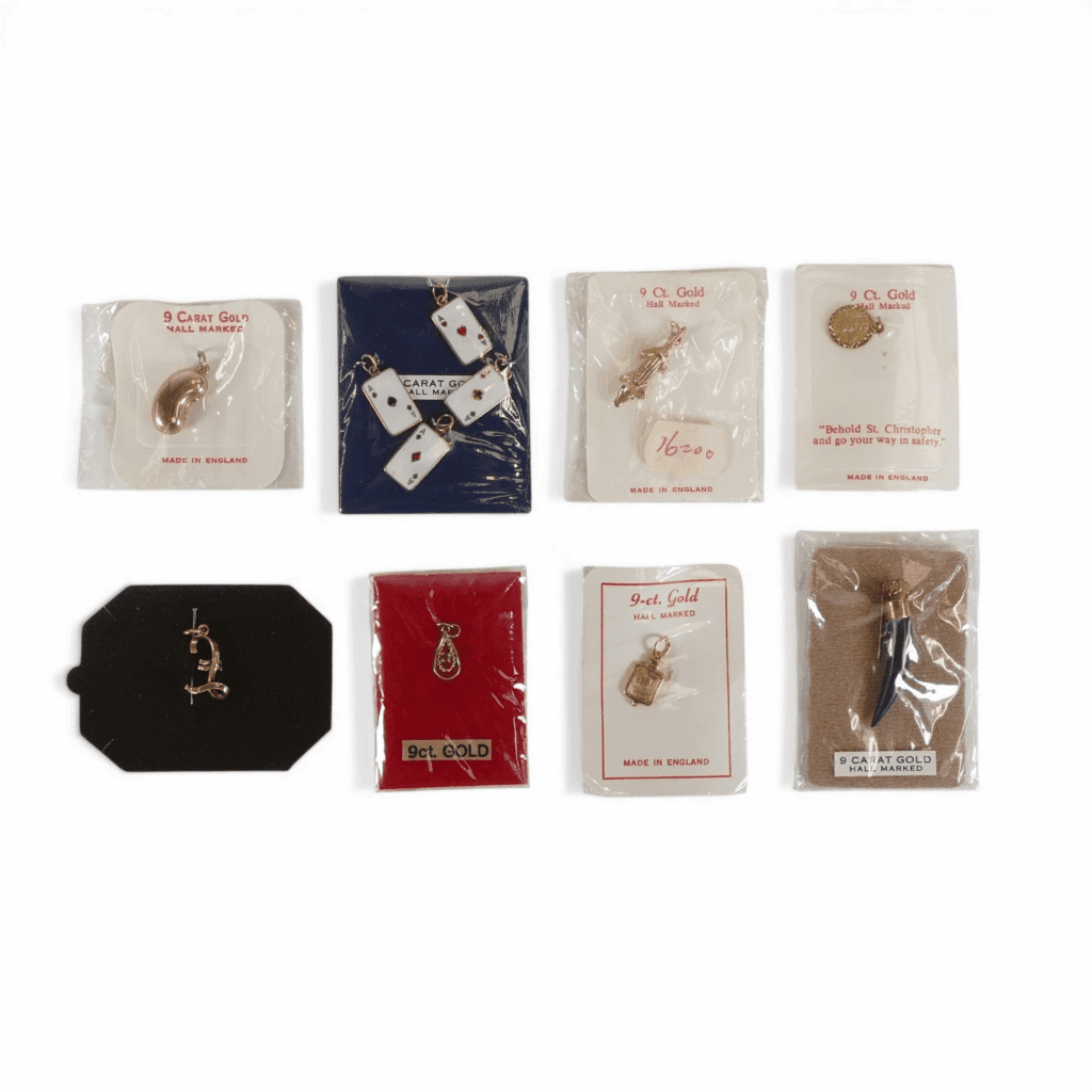 11 x small vintage 9ct gold charms / pendants, old 'new stock' mostly still sealed so weighing not possible